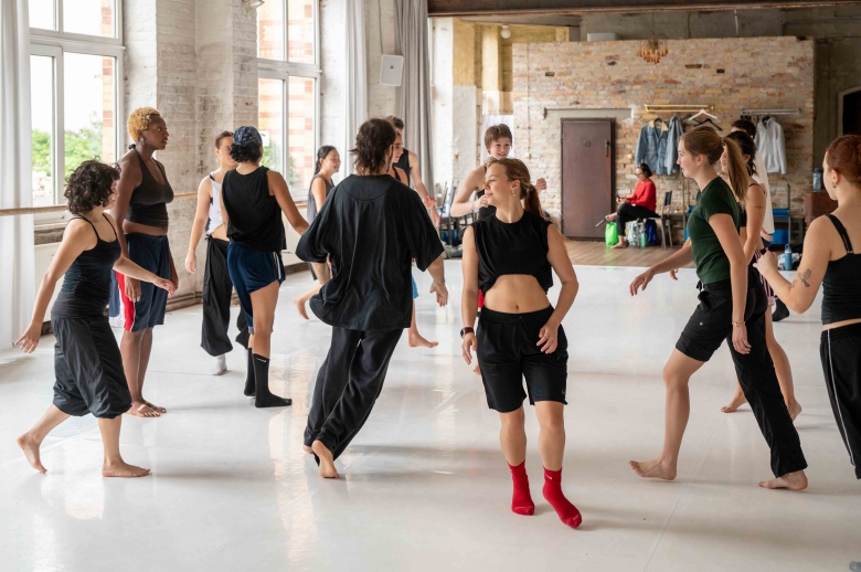 A group of dancers running around in a circle during a training session in a dance studio