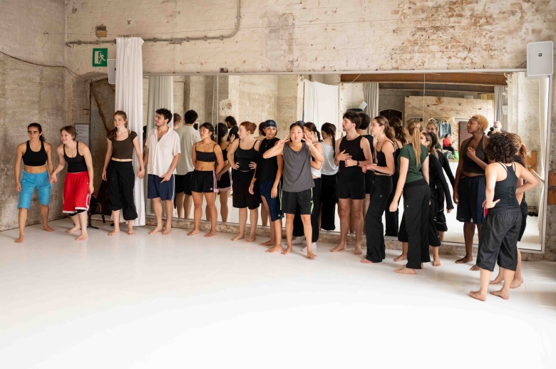 A group of dancers standing during a training session in a dance studio