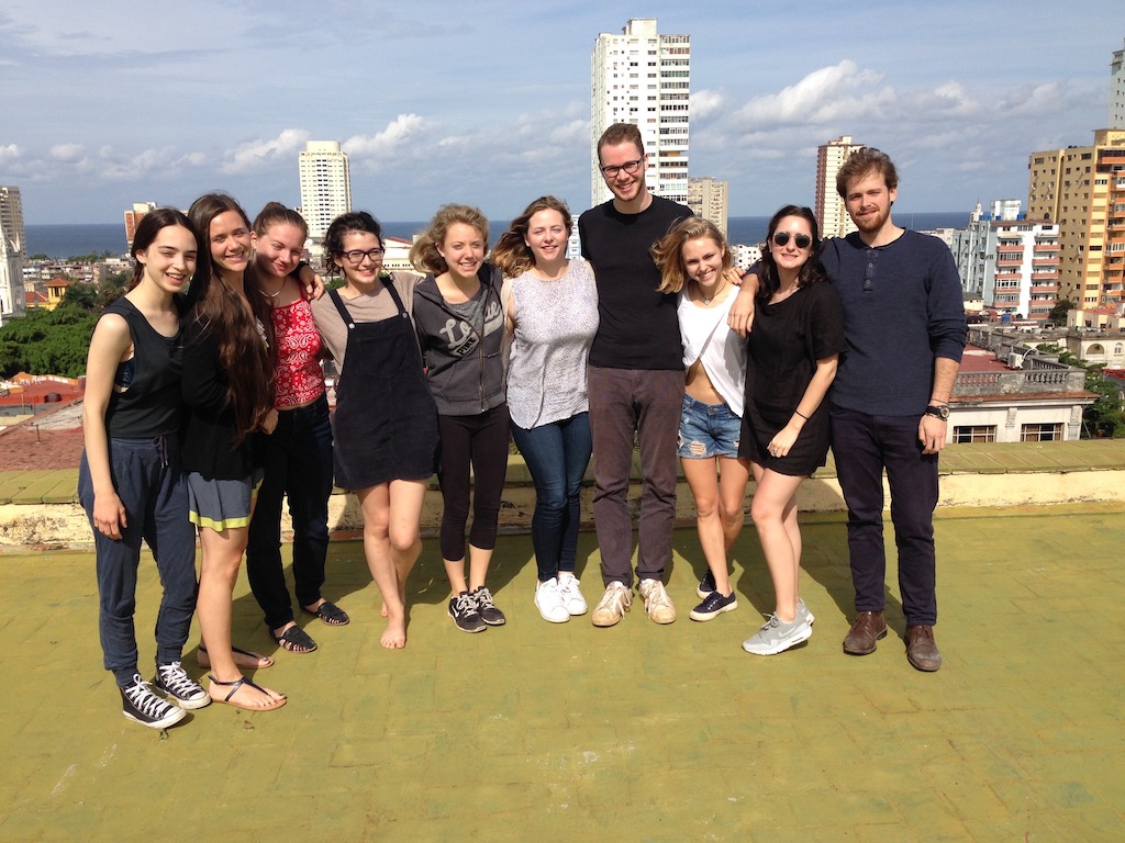 Group of students pose for a photo on a rooftop with the skyline of Havana, Cuba in the background.