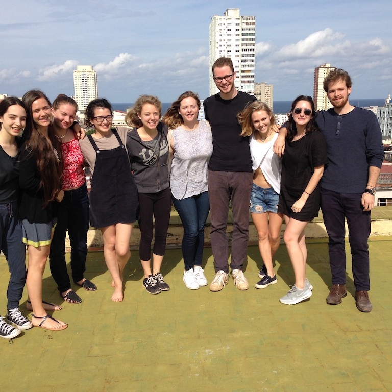 Group of students pose for a photo on a rooftop with the skyline of Havana, Cuba in the background.