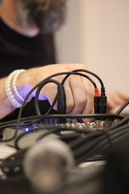 Audio cables with microphones and a hand adjusting a knob on the mixer.
