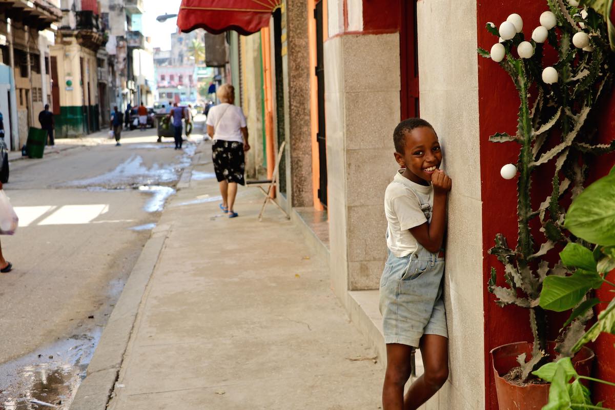 Child standing next to a wall on the streets of Havana.
