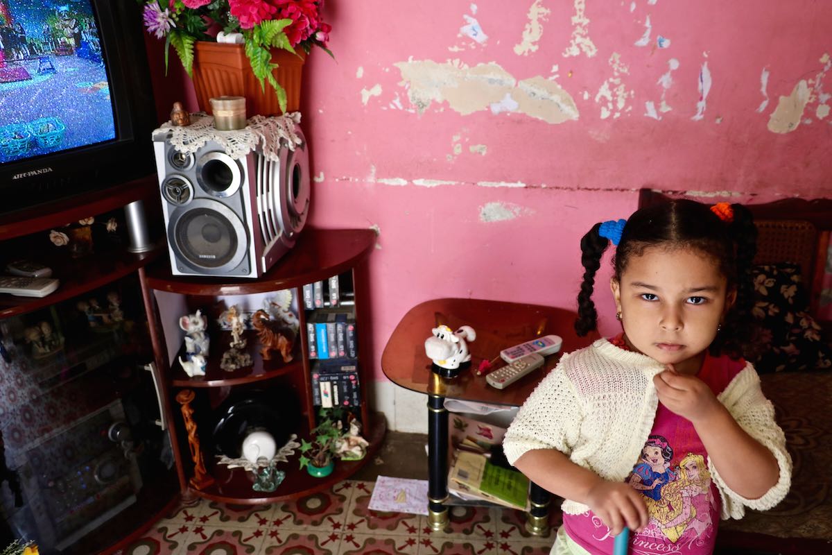 Little girl in her living room in front of the television in Havana, Cuba.
