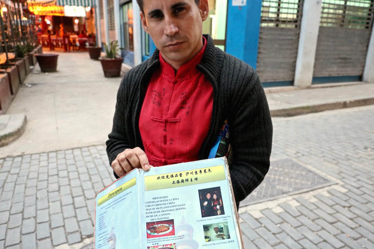 Cuban man holds out a Chinese menu in Havana.