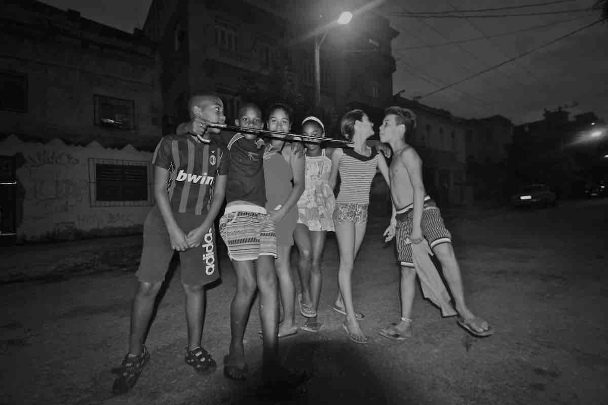 Black and white photo of a group of Cubans on the street at night in Havana.