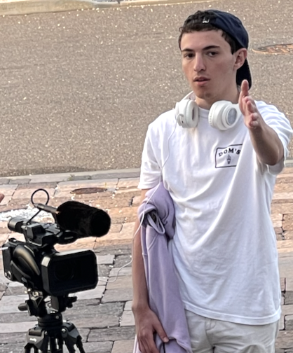 Male student wearing a hat with a camera on a film production set.