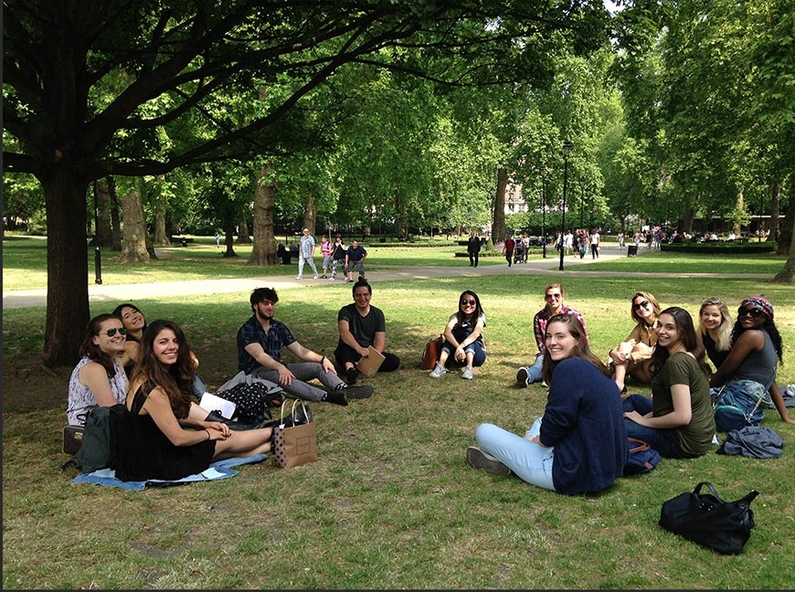 Group of students seated on the grass in Russell Square on a sunny day.