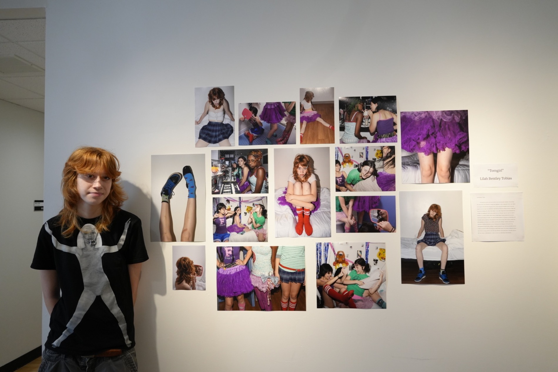 A Tisch Summer High School Photography student stands next to a display of their photography and imagery