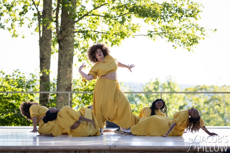 The women of LDC performing at Jacob’s Pillow On The Road Tour, wearing bright yellow, photographed in mid-performance on an outdoor stage