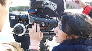 Young woman looking through a camera.