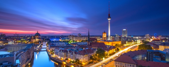 Aerial shot of the city of Berlin showing a river, buildings, monuments, and the Berlin TV Tower.