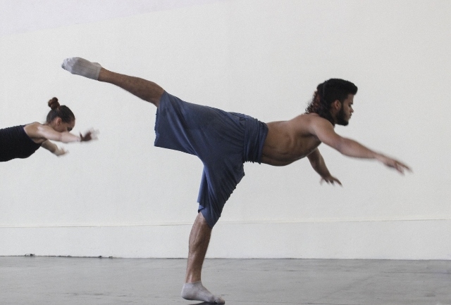 Dancers training in a studio, balancing on one foot with other leg extended behind them.