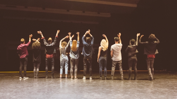 a still of performers on stage during rehearsal