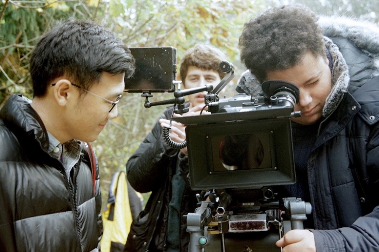 Film students looking through a 35mm camera. 