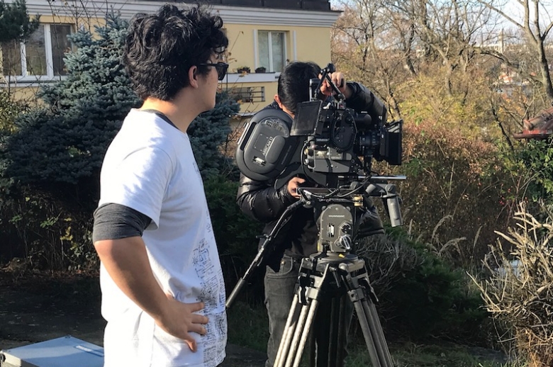 Filmmaker standing in front of a 35mm camera, filming an exterior shot.