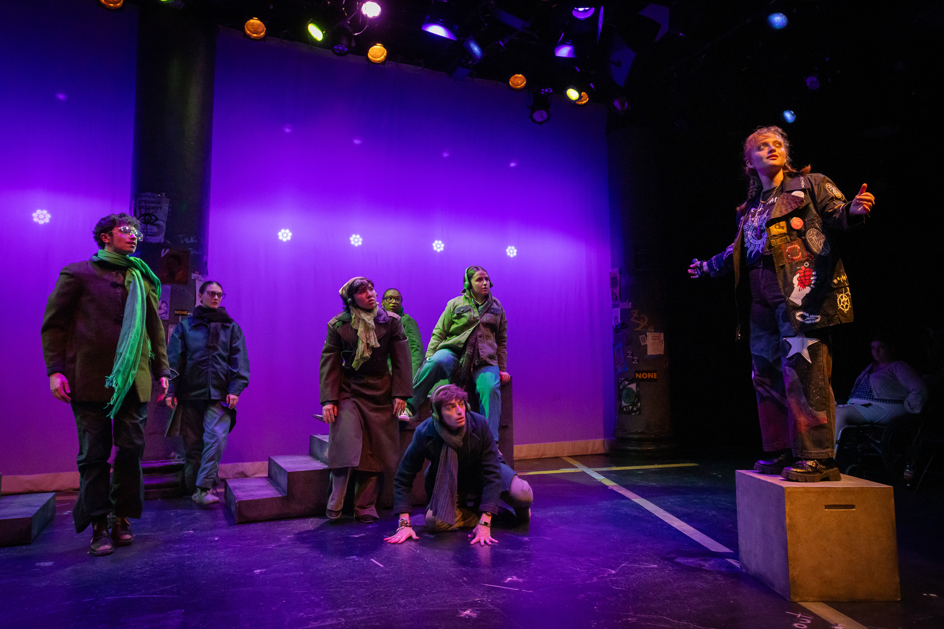 a group of people on a stage, with one person standing on a wooden box gesturing
