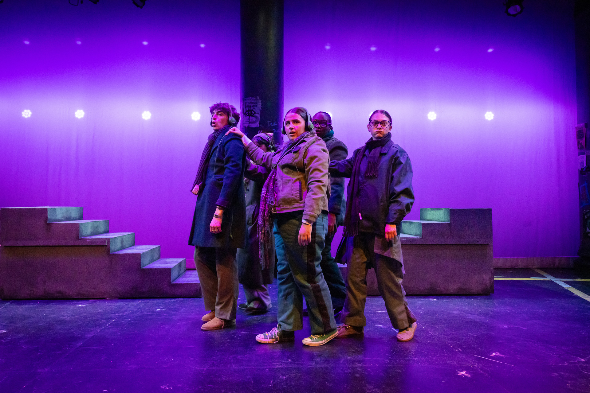 people on a stage looking towards the audience with a purple background