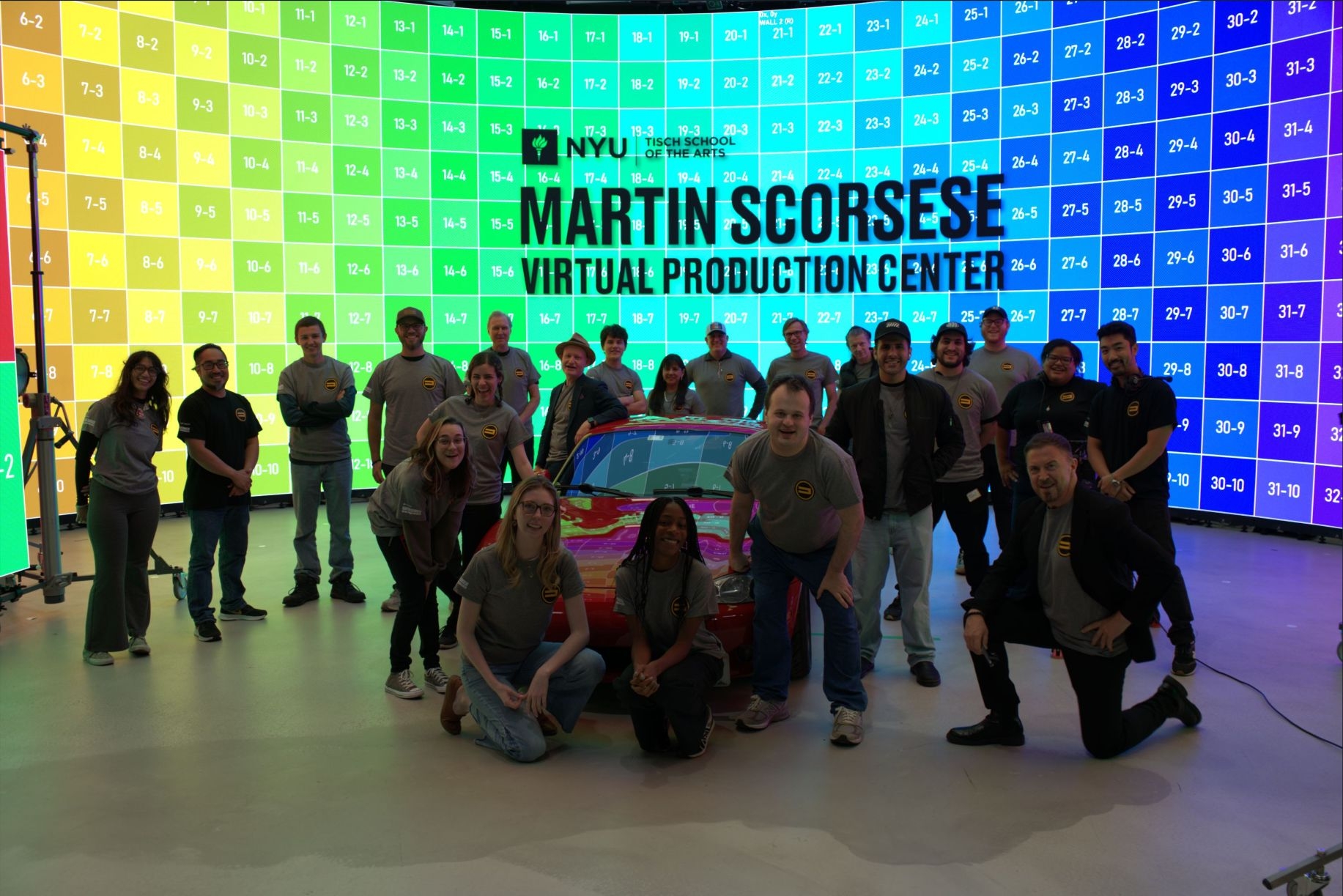 participants gathered around a red sports car in front of an LED volume wall